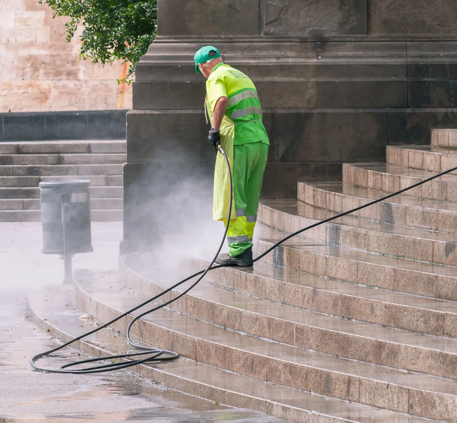 Stone steps being pressure washed, the cleaned half bright against the grime