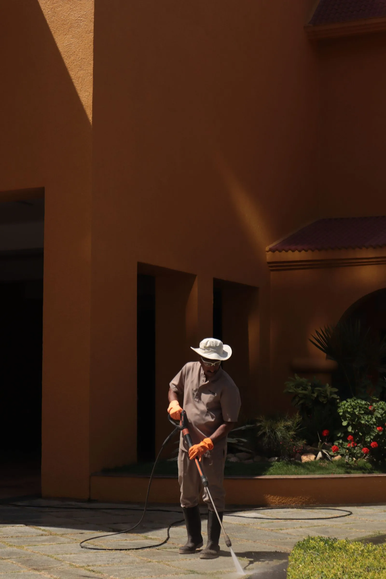 A worker pressure washing a paved walkway clean