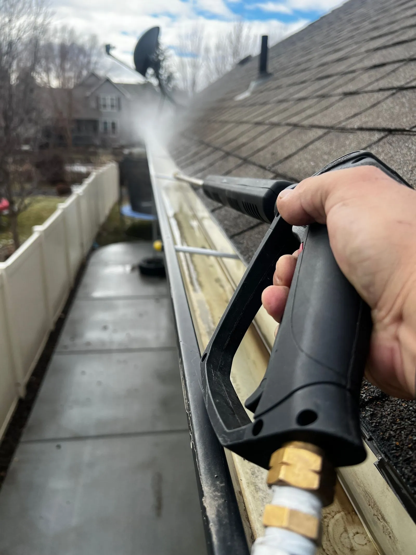 Close-up of a gutter being cleared with a pressure washer