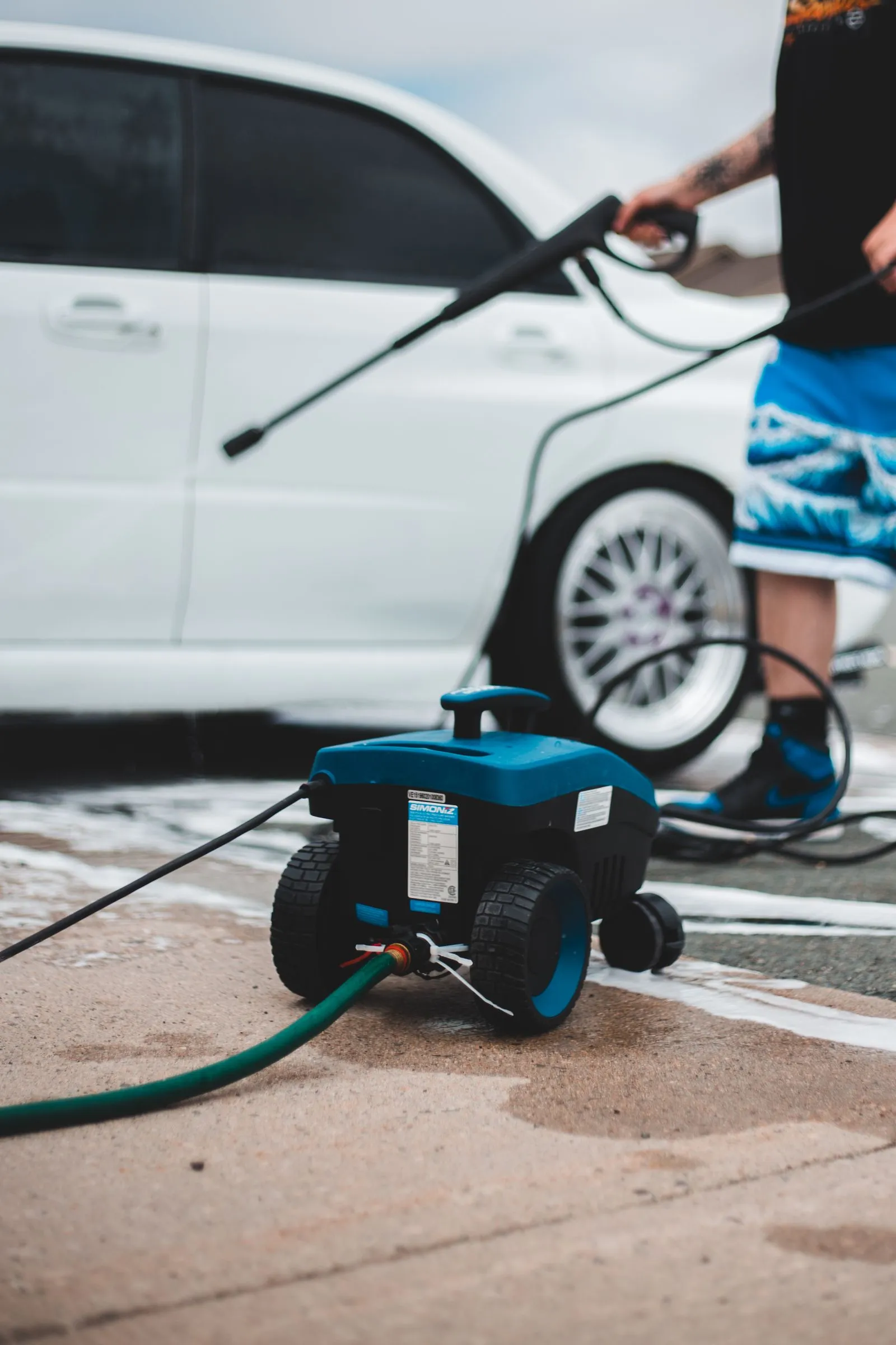 A pressure washer and hose set up on a driveway before a job